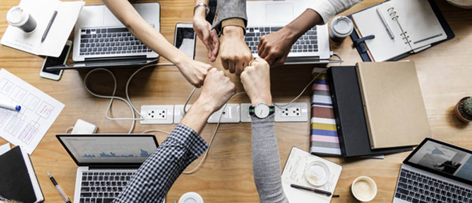 Team members fist-bumping over a work desk